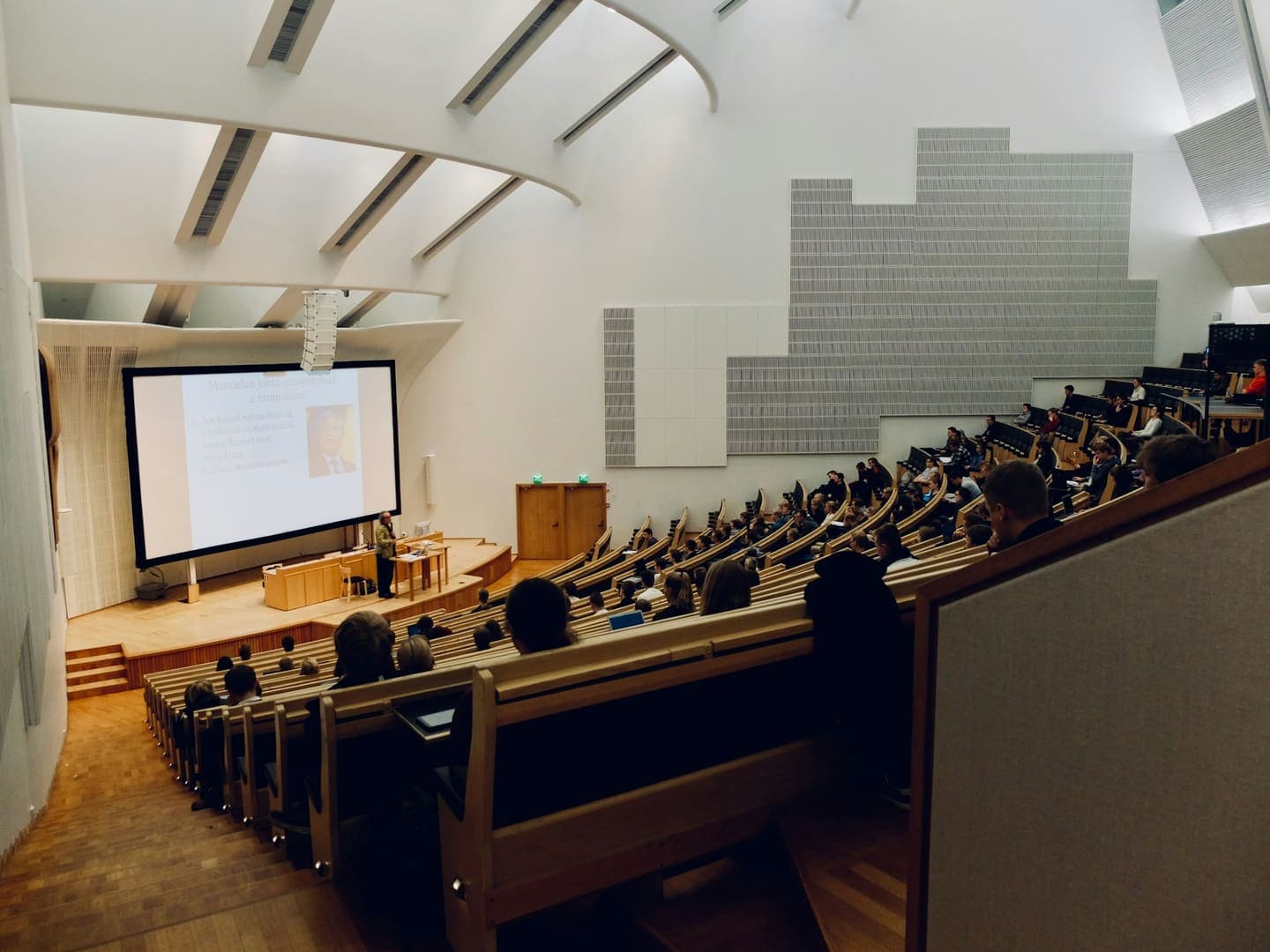 Un amphithéâtre rempli d'étudiants pendant un cours projeté à l'écran