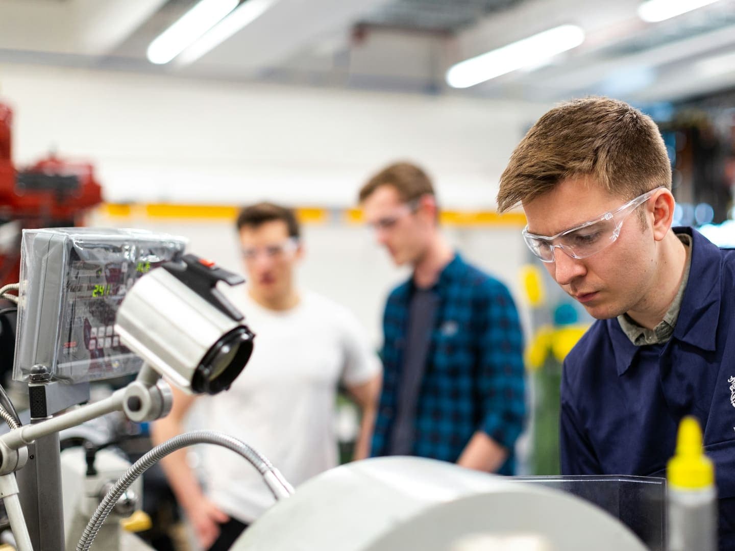 Des apprentis en lunettes de protection observent une machine en atelier