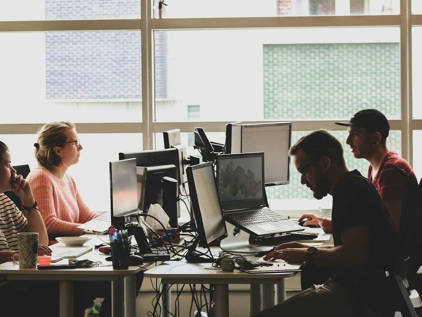 Une équipe de développeurs travaille sur plusieurs écrans dans un bureau lumineux