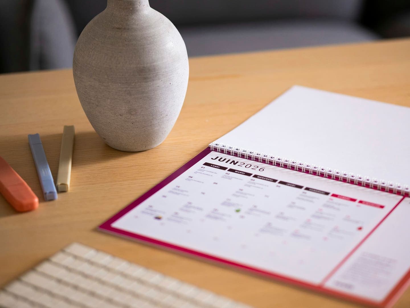 Un agenda mensuel ouvert sur un bureau à côté d'un vase